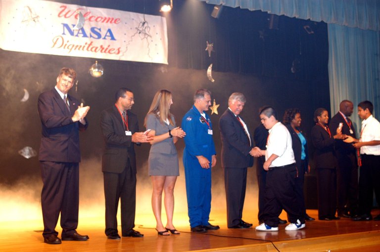 KENNEDY SPACE CENTER, FLA. -- During a visit to Howard A. Doolin Middle School, Miami, Fla., Center Director Jim Kennedy (shaking hands, center) and other NASA and KSC representatives are greeted by students on stage. With Kennedy on stage are (left to right), Jim Gerard, Aerospace Education Services Program (AESP) representative; Steve Lewis, assistant to Kennedy; Amber Marek, with KSC External Relations; David Wolf, astronaut; Kennedy; Les Gold, AESP representative; Burdette Brown; and Patricia Leonard and Clarence Bostic, Education Programs and University Research Division. Doolin Middle School is one of 100 to take part in the NASA Explorer Schools program. Kennedy is talking with students, the next generation of explorers, about our destiny as explorers, NASA?s stepping stone approach to exploring Earth, the Moon, Mars and beyond, how space impacts our lives, and how people and machines rely on each other in space. KENNEDY SPACE CENTER, FLA. -- During a visit to Howard A. Doolin Middle School, Miami, Fla., Center Director Jim Kennedy (shaking hands, center) and other NASA and KSC representatives are greeted by students on stage. With Kennedy on stage are (left to right), Jim Gerard, Aerospace Education Services Program (AESP) representative; Steve Lewis, assistant to Kennedy; Amber Marek, with KSC External Relations; David Wolf, astronaut; Kennedy; Les Gold, AESP representative; Burdette Brown; and Patricia Leonard and Clarence Bostic, Education Programs and University Research Division. Doolin Middle School is one of 100 to take part in the NASA Explorer Schools program. Kennedy is talking with students, the next generation of explorers, about our destiny as explorers, NASA?s stepping stone approach to exploring Earth, the Moon, Mars and beyond, how space impacts our lives, and how people and machines rely on each other in space.
